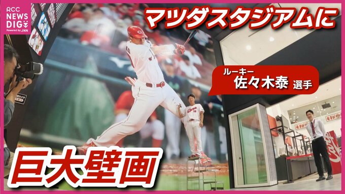 カープ期待の“大型ルーキー”が大抜擢！　マツダスタジアムの正面グッズショップの壁に佐々木泰選手の壁画　本人登場でサインも書き入れ|TBS NEWS DIG