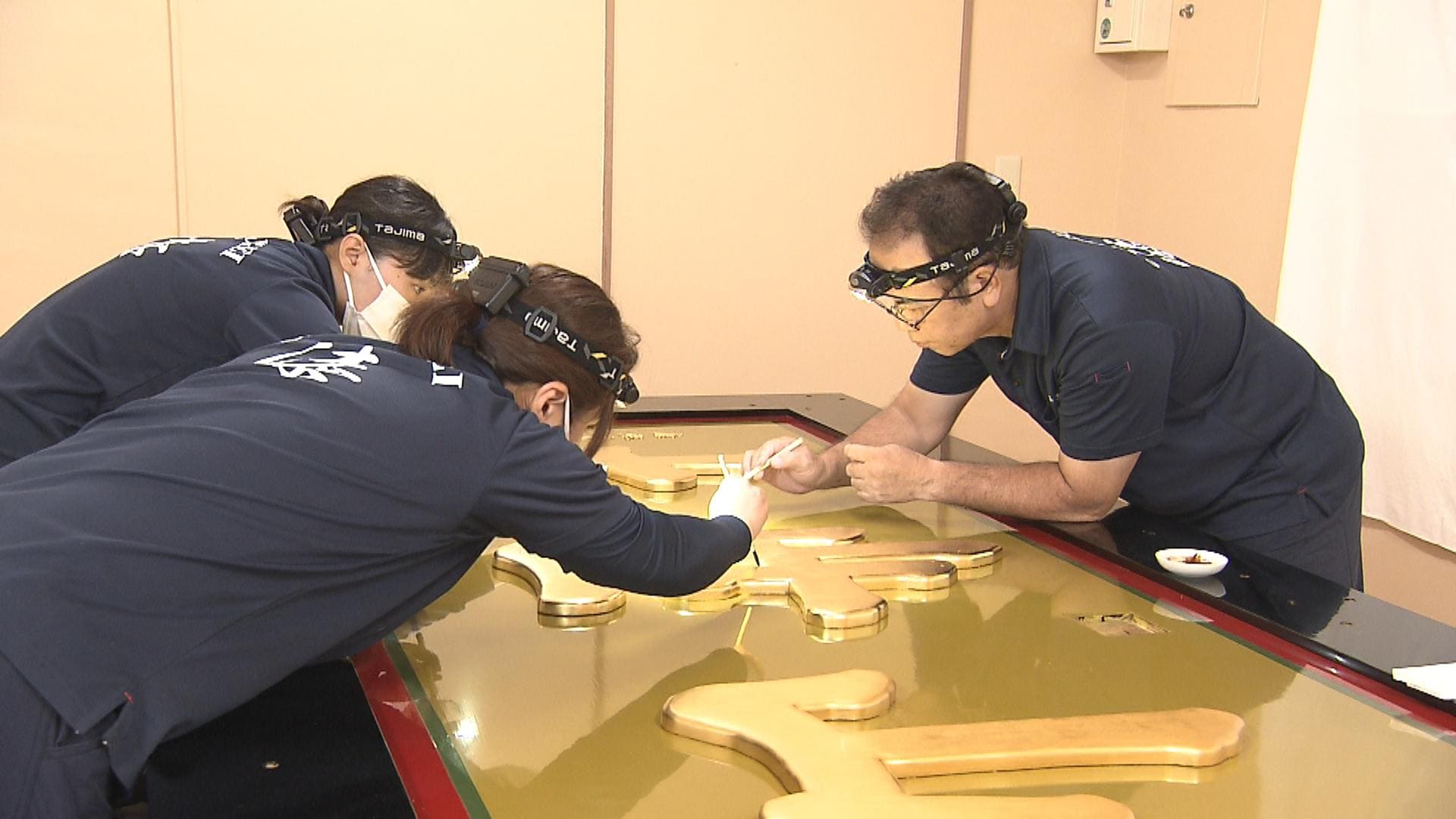 首里城正殿の「扁額」 最終工程の「金薄磨」 漆職人が丁寧に作業