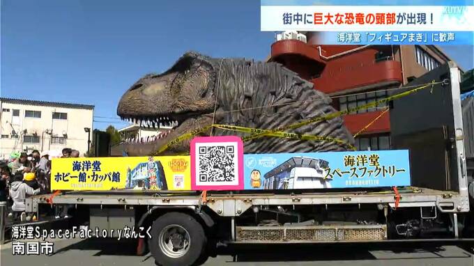 街中に巨大な恐竜の頭部が出現！ティラノサウルスがパレード？「もちまき」ならぬ「フィギュアまき」？海洋堂の人気施設リニューアルをPR【高知】　|　高知のニュース・天気｜KUTV NEWS | KUTVテレビ高知