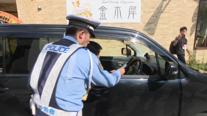 「法定速度引き下げ」を知らせるパンフレットを手渡す警察官