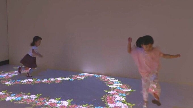 デジタルアートの床の上で楽しむ子供たち
