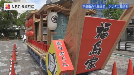 店のシンボル “釣り鐘” や “ランタン” で飾る 中華街の老舗薬局の前
