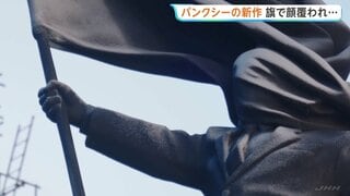 旗で顔覆われたスーツ姿の巨大な像 バンクシー新作がロンドン中心部に現る 「盲目的な愛国心への批判だ」との考察も| TBS CROSS DIG with Bloomberg