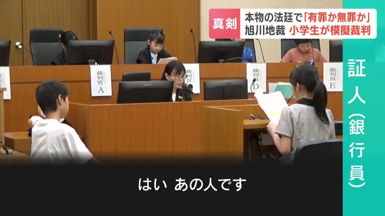 被告人を指さして証言する銀行員役の小学生