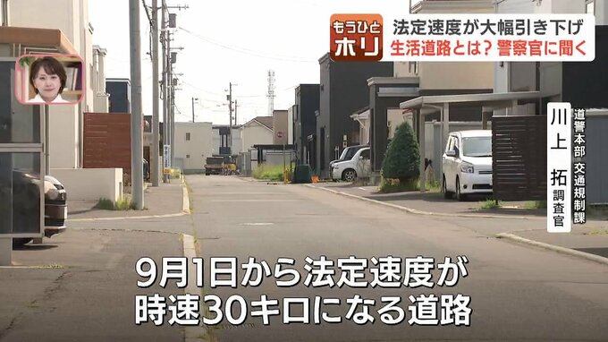 現地で法定速度が時速30キロに変更される生活道路を解説する警察官